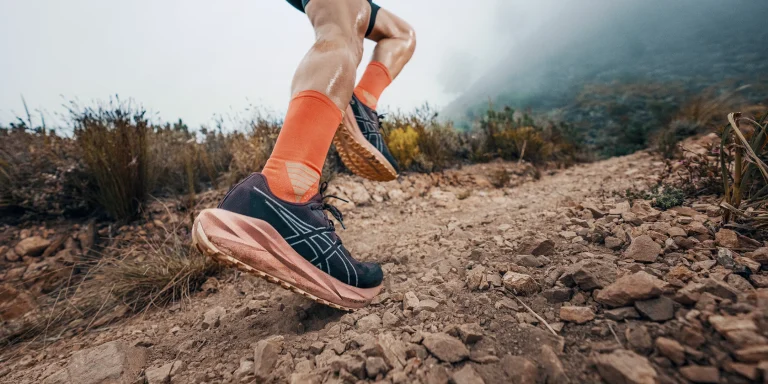 jambes d'un coureur dans un chemin de terre avec des chaussures noires et roses
