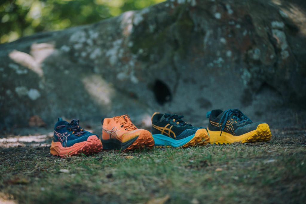 4 chaussures de running posées sur le sol sur un chemin