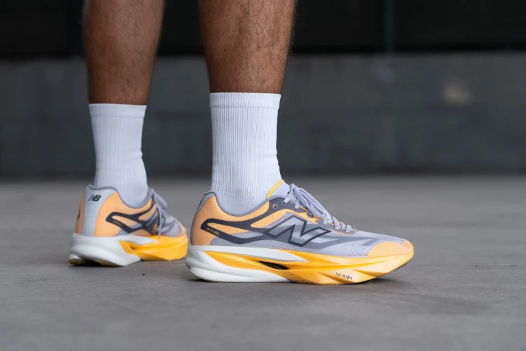 les jambes d'un homme portant une paire de chaussures de running new balance grise et orange