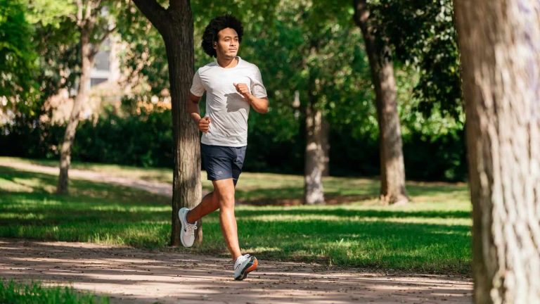 Jeune homme courant dans un parc dans ses écouteurs
