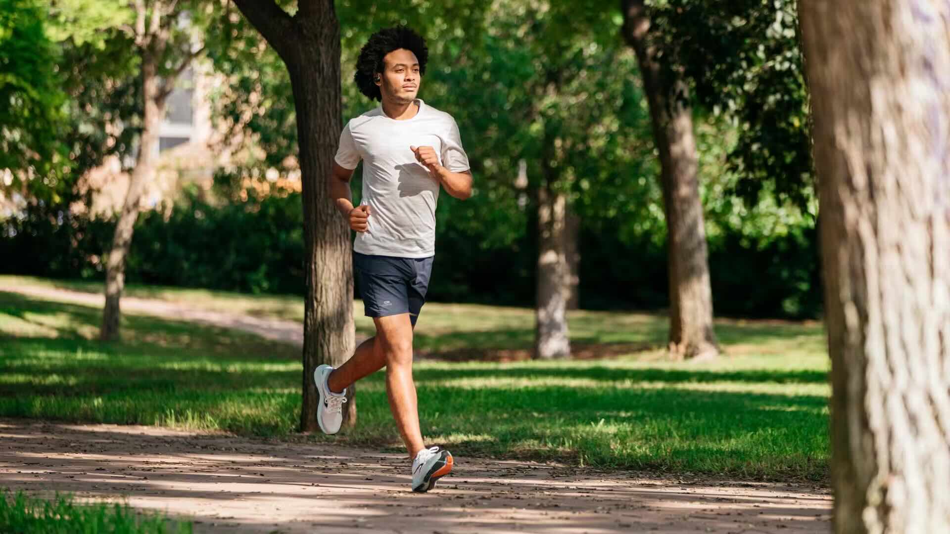 Jeune homme courant dans un parc dans ses écouteurs
