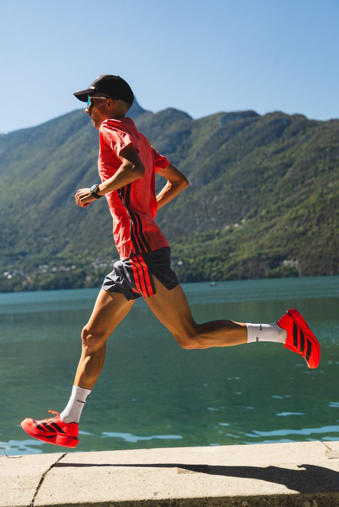coureur avec des chaussures de running rose et un t-shirt rose courant au bord d'un lac
