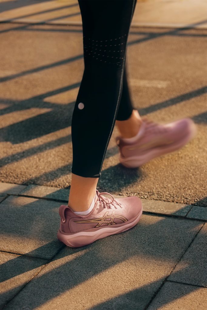 Pieds d'une runneuse portant des chaussures roses asics.
